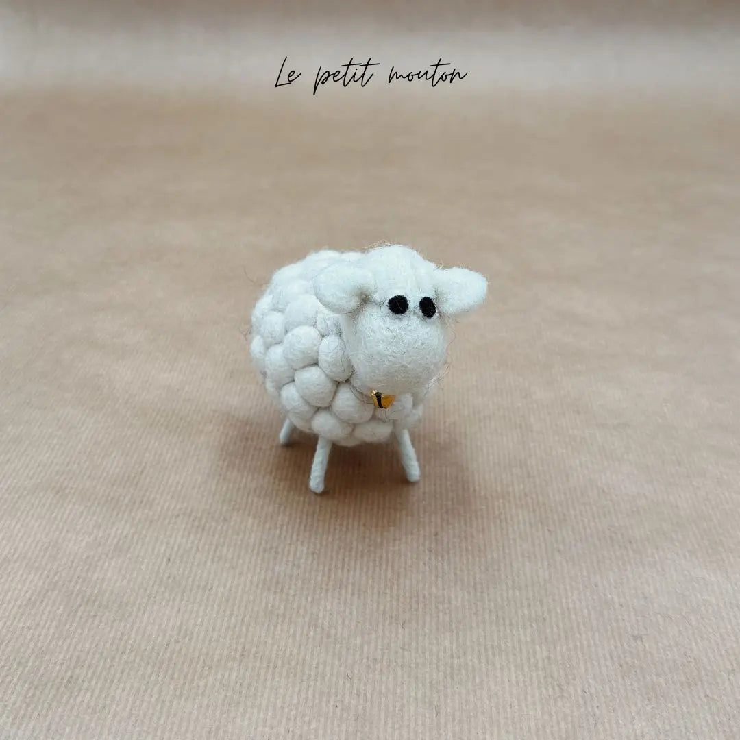 Petit mouton blanc New Heidi en feutrine de laine bouclée artisanale avec une petite cloche, vue de face.