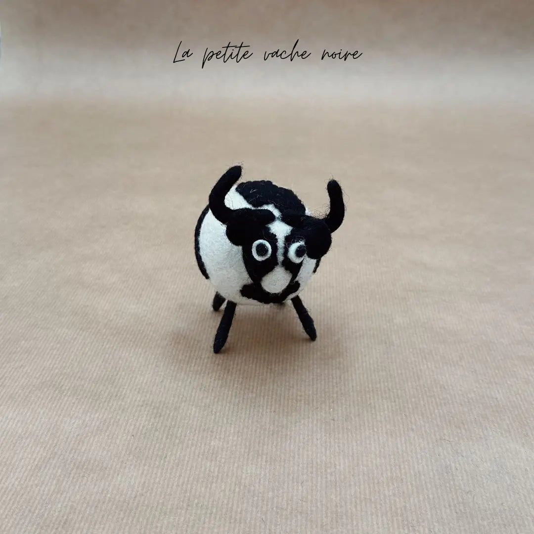 Petite vache boule noire et blanche New Heidi en feutrine artisanale vue de face.