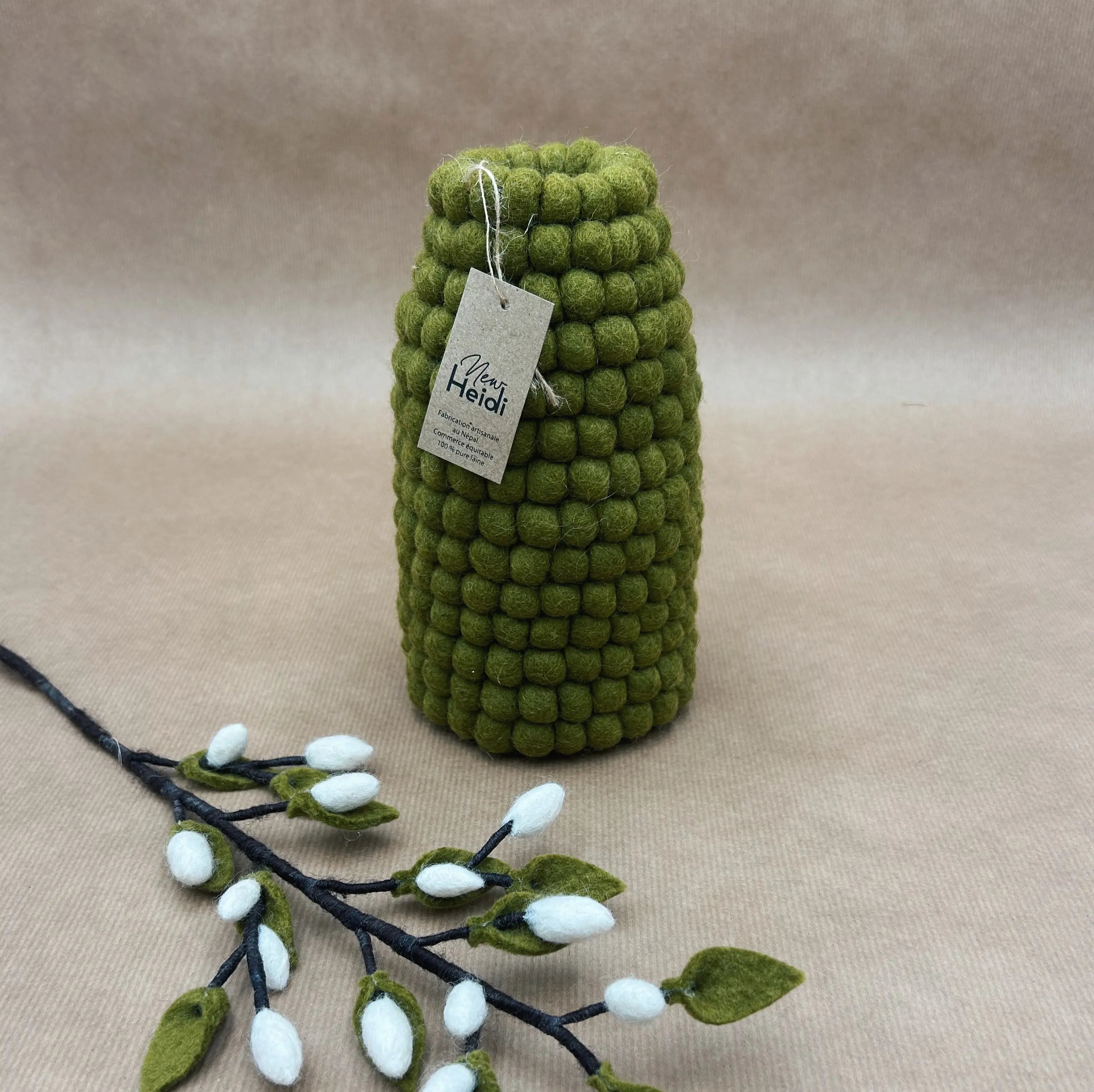 Vase en laine feutrée kaki New Heidi avec son étiquette artisanale, accompagné d'une branche de chatons de saule.